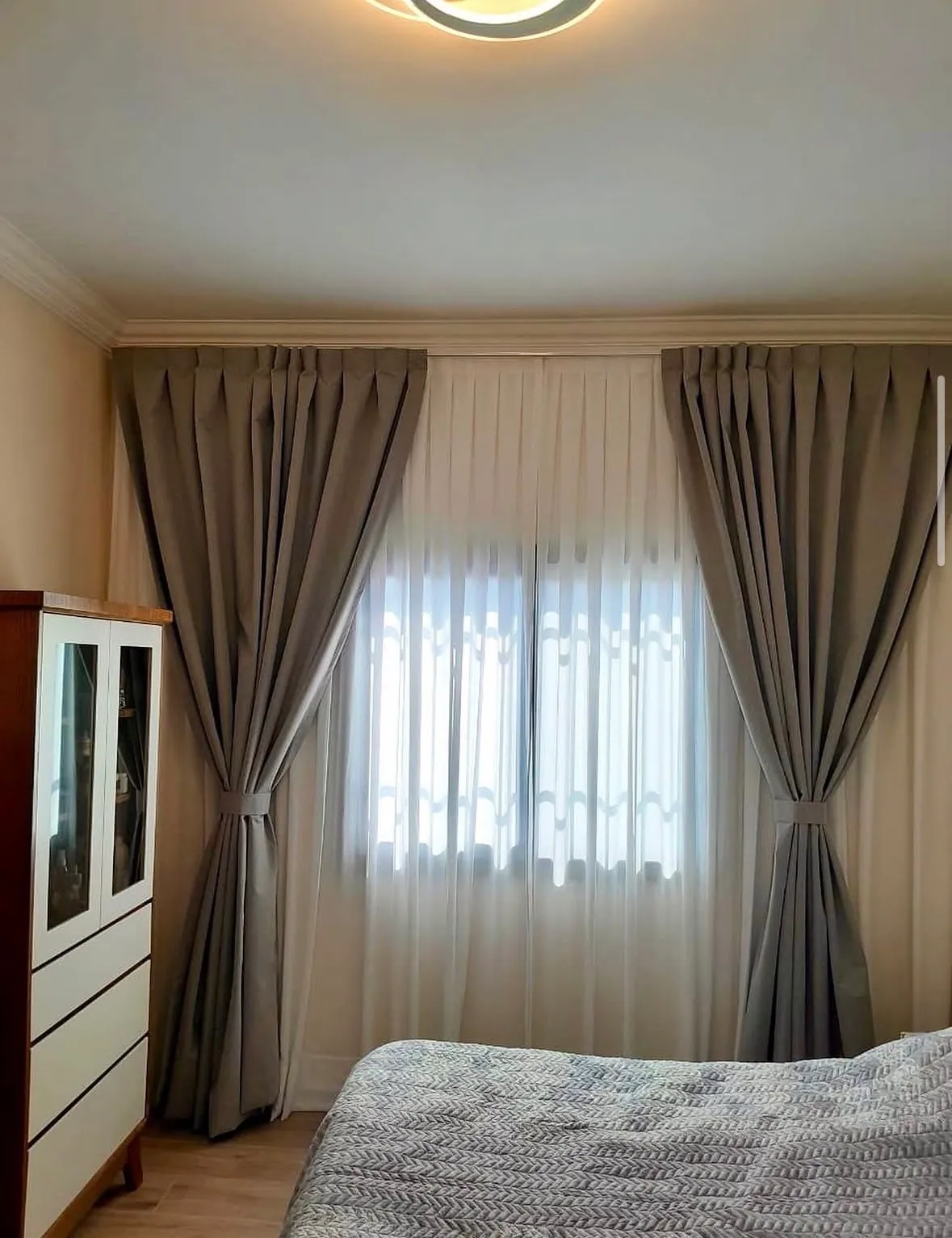 Cortina con barral y sujetadores sobre voile en un dormitorio