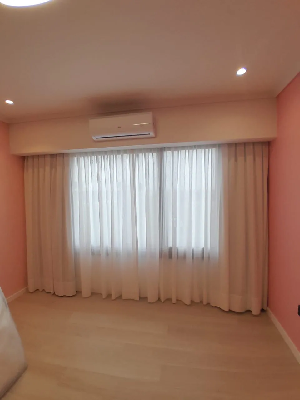 Cortinas con cenefa y gasa en un dormitorio de paredes cálidas
