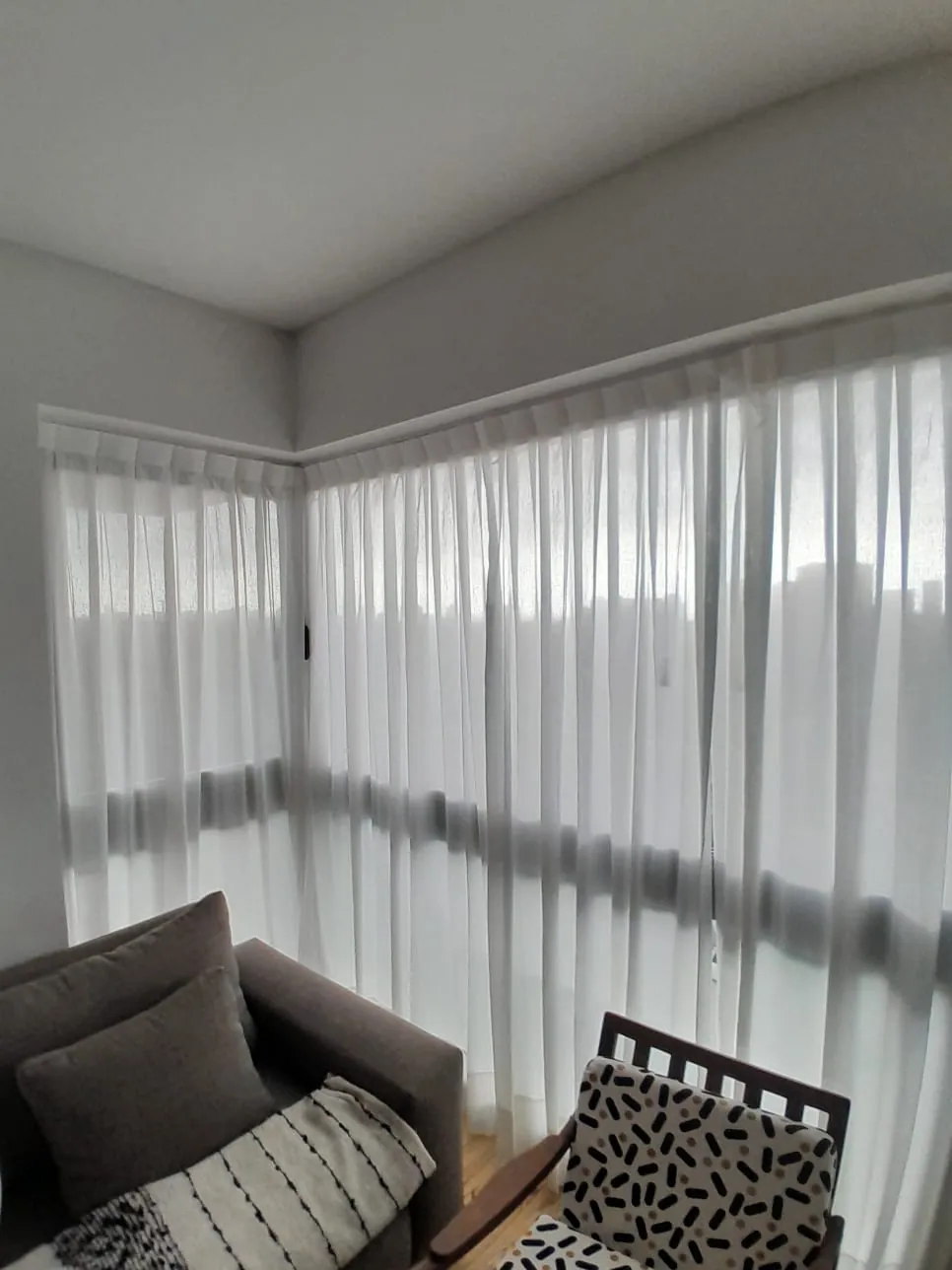 Cortinas de gasa en esquina de un living con sillón y sofá